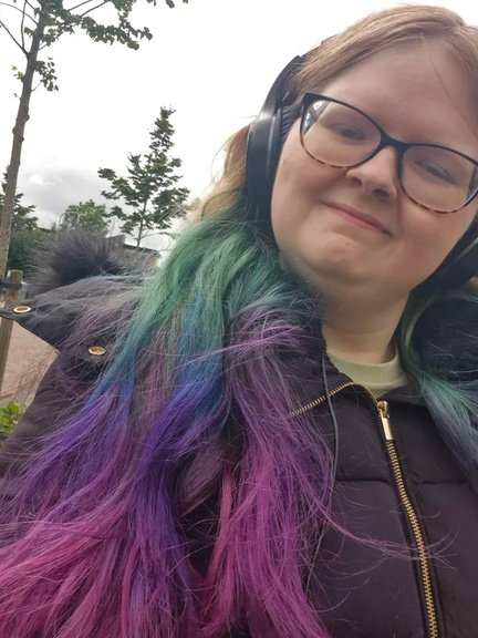 Jantina Mulder met een koptelefoon op en gekleurd haar in groen, blauw en paars